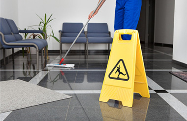 Man with mop and wet floor sign